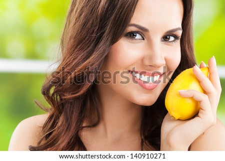 Portrait of young happy smiling woman with lemon, outdoors