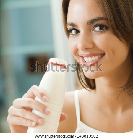 Portrait of young happy woman drinking milk at home