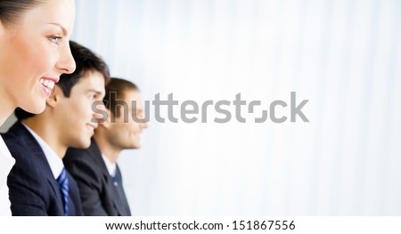 Three young happy smiling successful businesspeople at meeting, presentation or conference, with copyspace