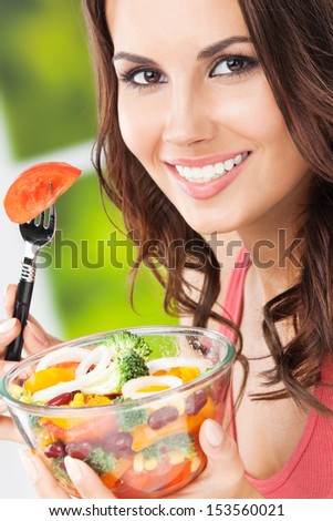 Portrait of happy smiling young woman with vegetarian vegetable salad, outdoors