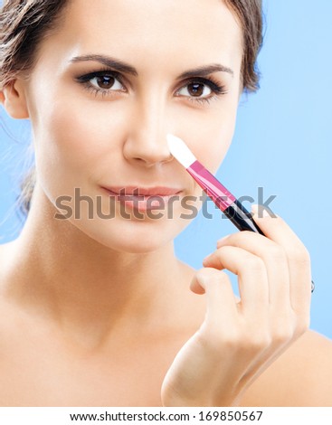 Young happy smiling woman with cosmetics brush, over blue background