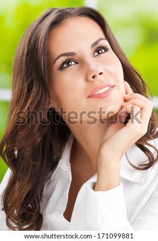 Portrait of young smiling cheerful thinking business woman at office