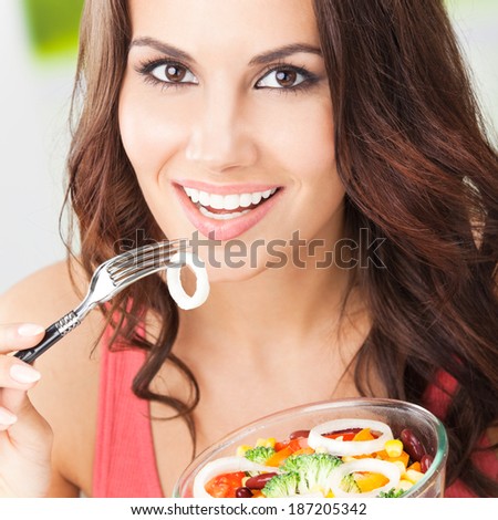 Portrait of happy smiling young woman with vegetarian vegetable salad, outdoors