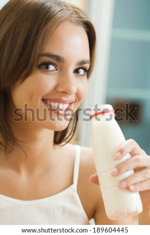 Portrait of young happy woman drinking milk at home