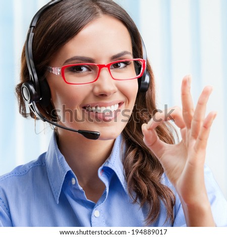 Portrait of happy smiling cheerful young support phone operator in headset, showing okay gesture, at office