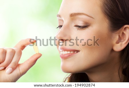 Portrait of woman with Omega 3 fish oil capsule, outdoors