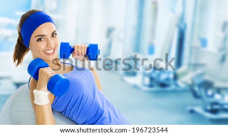 Young happy woman doing fitness exercise, at fitness club or center, with copyspace
