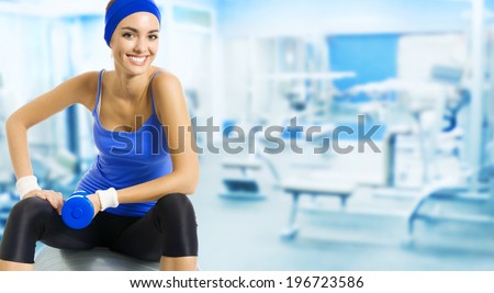 Young happy woman doing fitness exercise, at fitness club or center, with copyspace