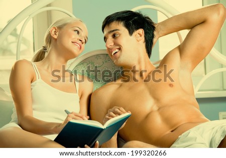 Young attractive happy smiling couple with notebook or organizer at home