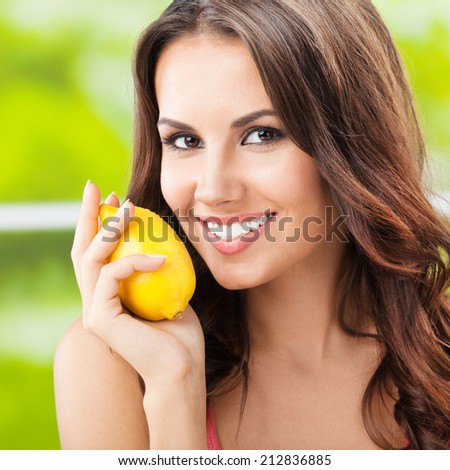 Portrait of young happy smiling woman with lemon, outdoors