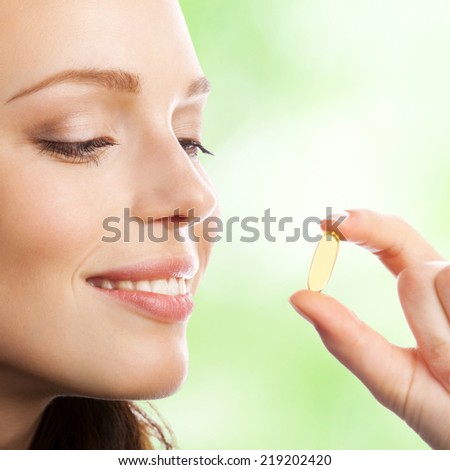 Portrait of woman with Omega 3 fish oil capsule, outdoor