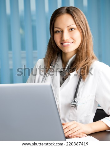 Portrait of cheerful female doctor working with laptop at office