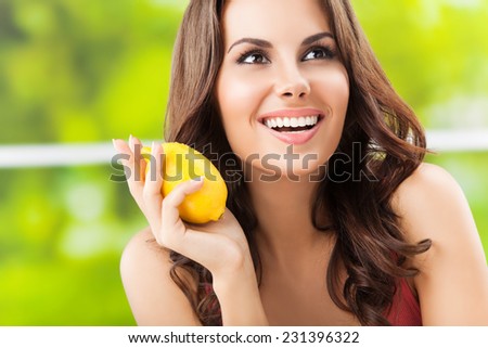 Portrait of young happy smiling woman with lemon, outdoor