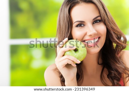 Portrait of young woman with green apple, outdoors, with copyspace