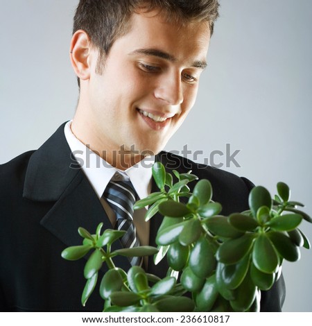 Young happy smiling businessman or student with flowerpot. Growing business concept.