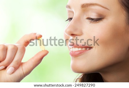 Young smiling woman with Omega 3 fish oil capsule, outdoor