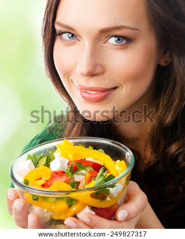 Young beautiful smiling woman with salad, outdoor