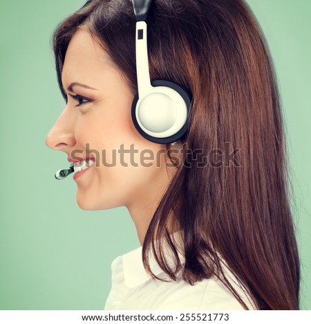 Profile view portrait of happy smiling cheerful customer support phone operator in headset, on green background