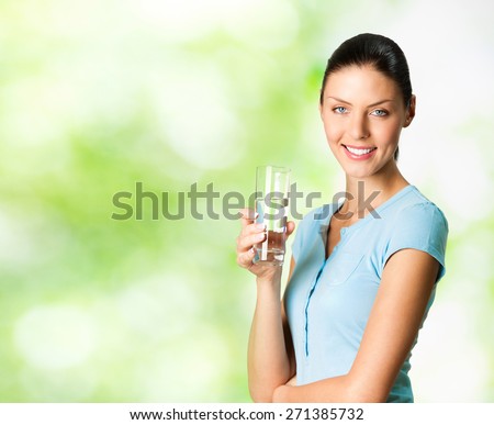 Young happy smiling woman with glass of water, outdoor, with blank copyspace area for text or slogan