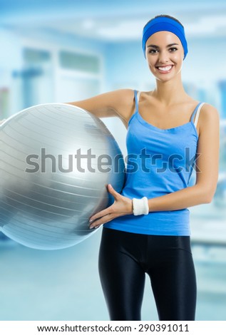 Young happy smiling woman in blue sportswear with pilates ball, at fitness club or center. Beauty and health concept.