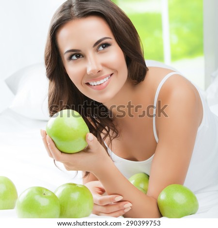 Young happy smiling brunette woman with green apples, indoors. Healthy eating, beauty and dieting concept.