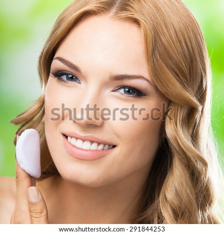 Portrait of happy smiling young lovely woman with cotton pad, outdoor. Visage and cosmetics concept.