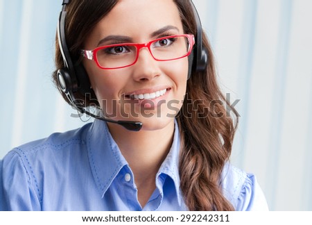 Portrait of happy smiling cheerful beautiful young female support phone operator in headset and glasses, at office. Customer assistance service concept.