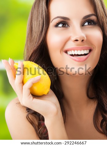 Portrait of young happy smiling lovely woman with lemon, outdoor