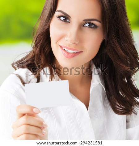 Happy smiling brunette businesswoman showing blank business or plastic card with copyspace area for slogan or text. Invitation concept.