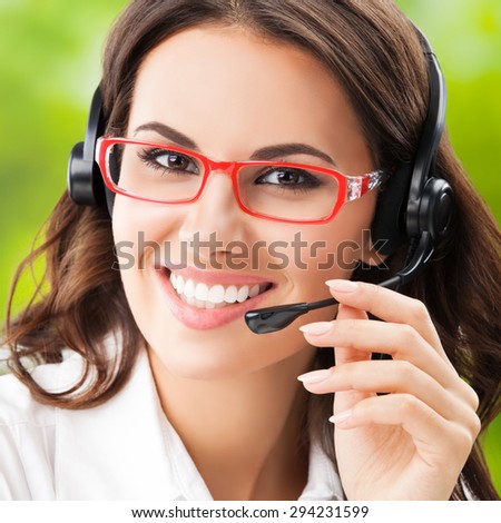 happy smiling cheerful young brunette businesswomen, support phone female operator or call center worker, in headset and glasses. Help and consulting concept.
