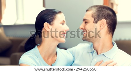 portrait of happy smiling lovely couple in blue casual smart clothing, looking at each other, at home
