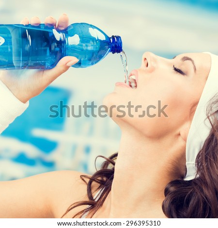 Young lovely woman drinking water, at fitness club or gym