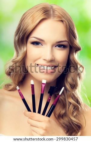 Happy smiling blond lovely woman with make up tools, outdoors. Beauty, visage and cosmetics concept.