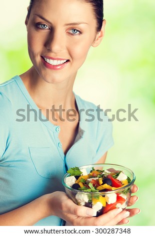 Portrait of young happy smiling lovely woman with salad, outdoors