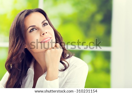 thinking smiling attractive brunette businesswoman looking up, at office