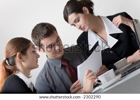Three business person looking at paper sheet and discussing something, smiling