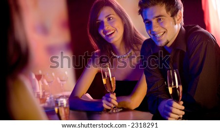 Young people with champagne glasses in restaurant, meeting