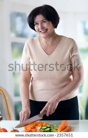 Elderly happy woman cooking at kitchen