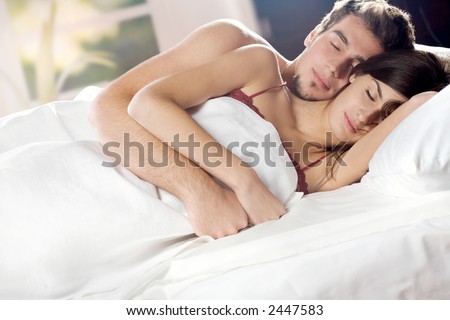 Young couple sleeping and hugging on the bed in bedroom