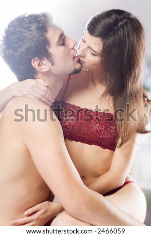 Couple kissing and hugging on bed in bedroom, in passion