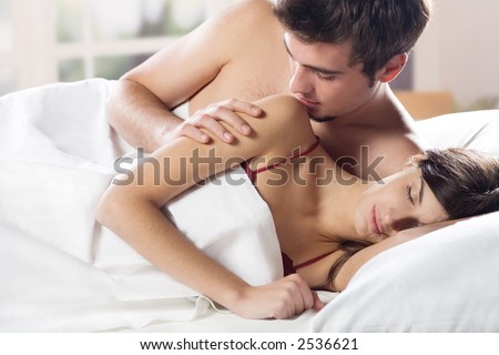 stock photo Young couple kissing and hugging on the bed in bedroom