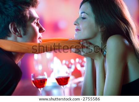 Young attractive happy couple kissing in restaurant, celebrating or on romantic date