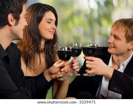 Two young happy smiling men flirting with attractive woman with red-wine, at celebration or party
