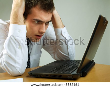 Young puzzled business man or student on laptop working or reading mail at the table
