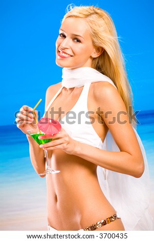 Young beautiful tanned happy sexy smiling blond woman in bikini with cocktail on tropical sea beach