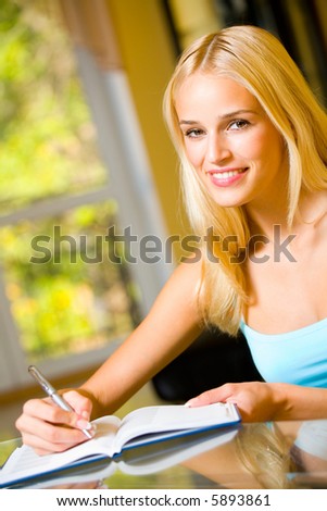 Portrait of beautiful smiling woman with notebook or organiser, indoors