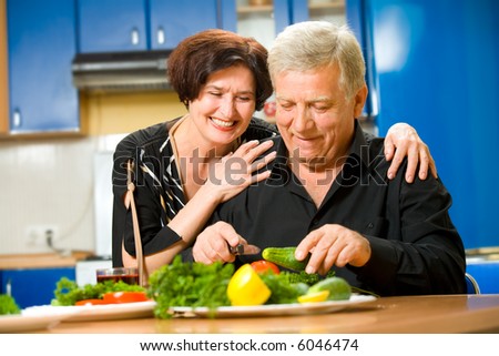 Elderly happy attractive smiling couple cooking at kitchen