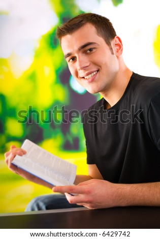 Portrait of young happy man reading book, outdoors