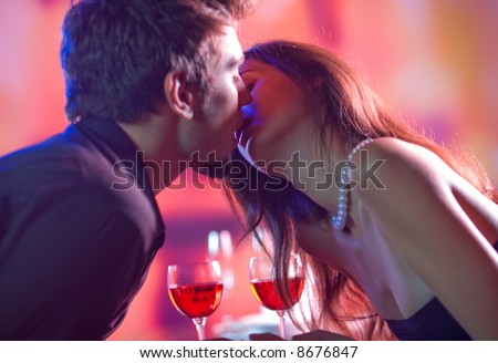 Young happy amorous couple kissing at restaurant