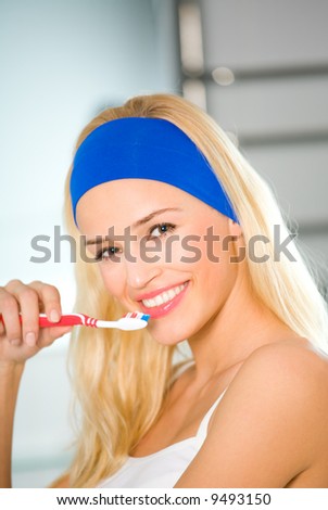 Young happy woman clean teeth by tooth-brush in bathroom